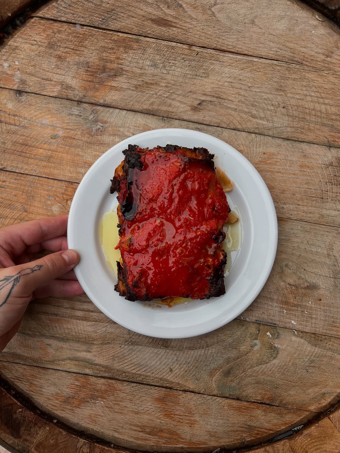 Prato de entrada com creme branco e molho vermelho, sobre madeira
